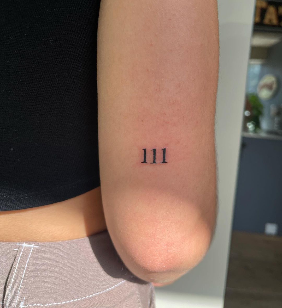 111 tattoo in the back of the arm of a white woman
