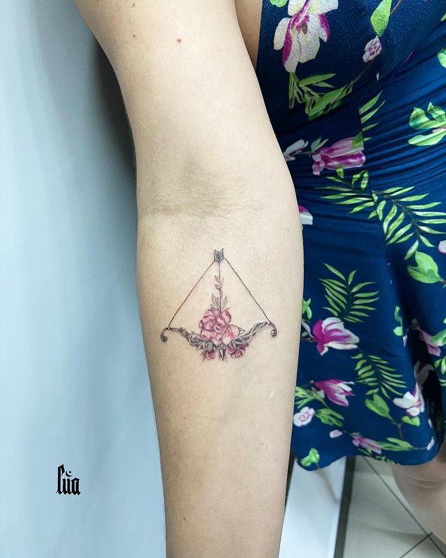 floral bow and arrow arm tattoo