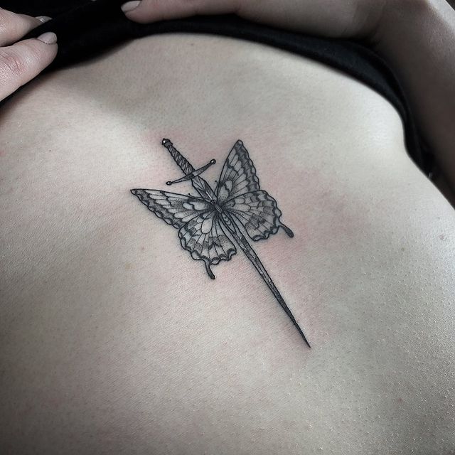 Tiny sternum butterfly and dagger tattoo